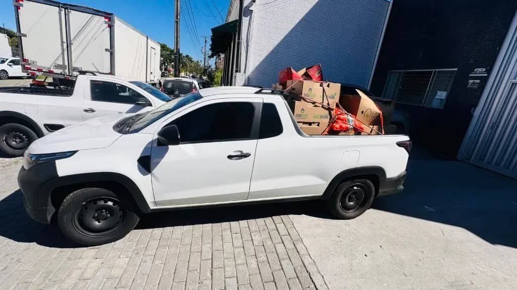 Picape branca com caixas amarradas na caçamba em um frete urbano em Curitiba
